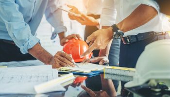 Contractor and engineer with blueprints discuss at a modern construction site, Engineers in mechanical factory reading instructions